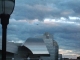 An airplane over the crumply silver art building.