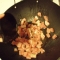 Pork in the wok with more ajwain being poured in.