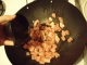 Pork in the wok with more ajwain being poured in.