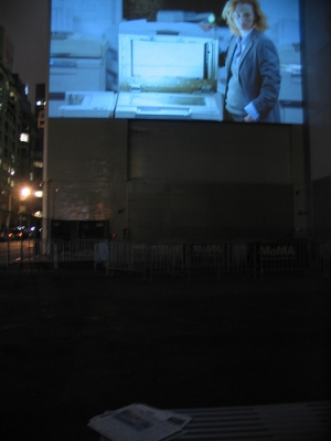 Tilda Swinton eyes a paper in the MoMA sleepwalkers public viewing area
