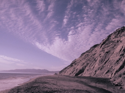 where the ocean meets land and land meets sky, the reflection of shadow fades to grey. 