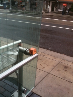 Balanced on a bus stop rail.